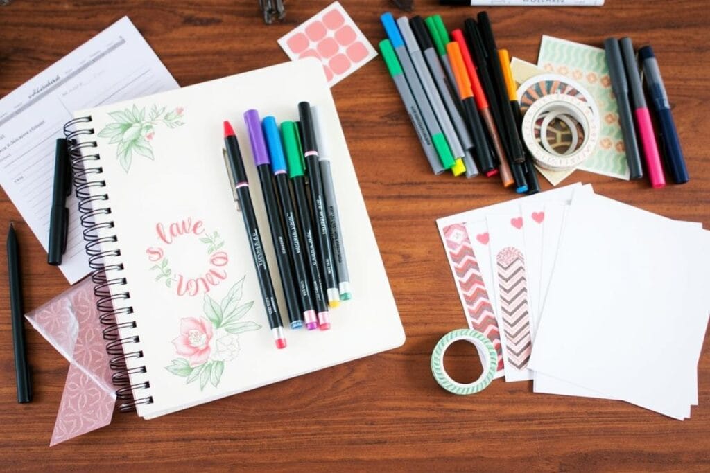 Material organizado para iniciar journaling: caderno, canetas coloridas e marcadores